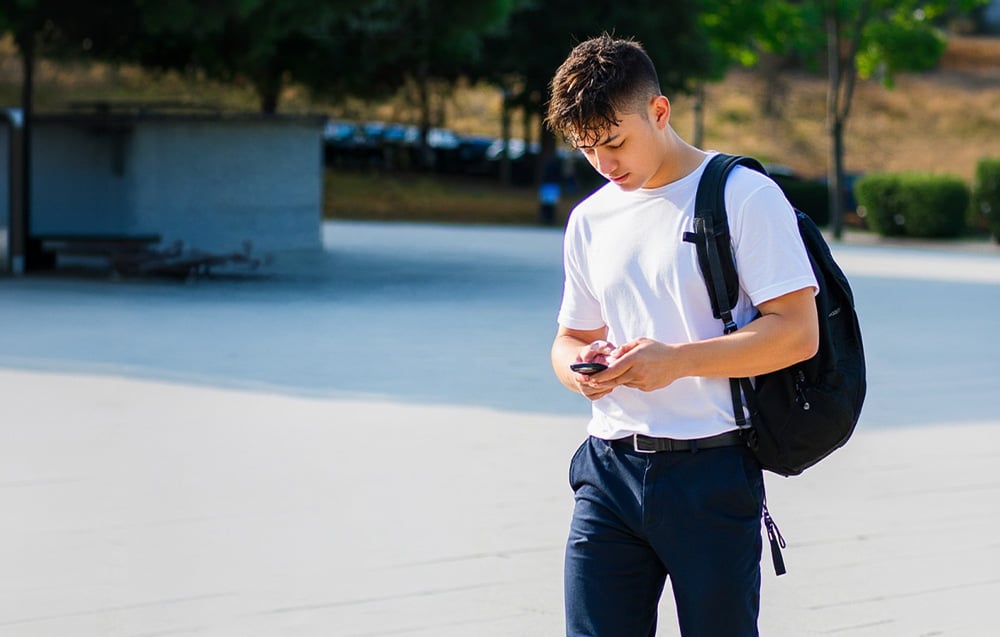 A young man with a backpack and a smartphone in his hand
