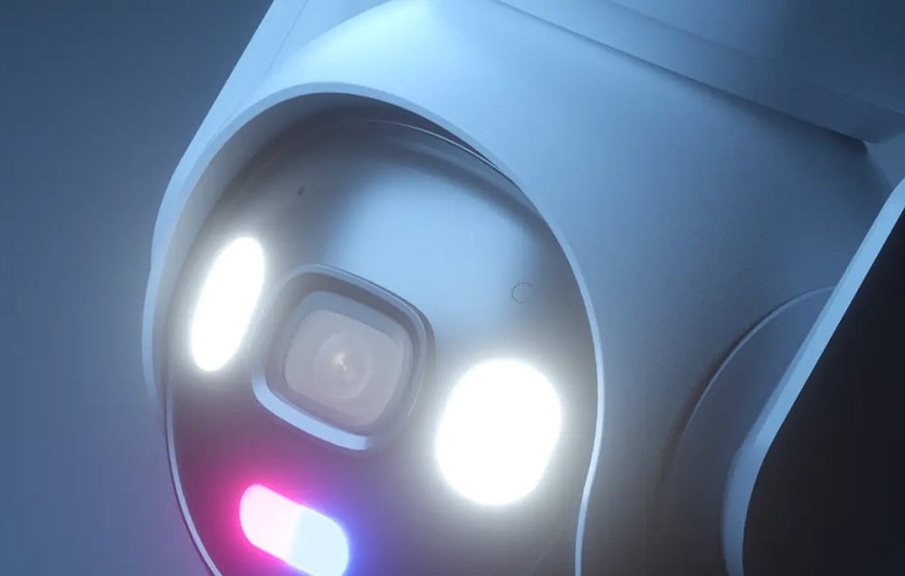 Close-up of the camera lens with two glowing white lights and one pink-blue LED below