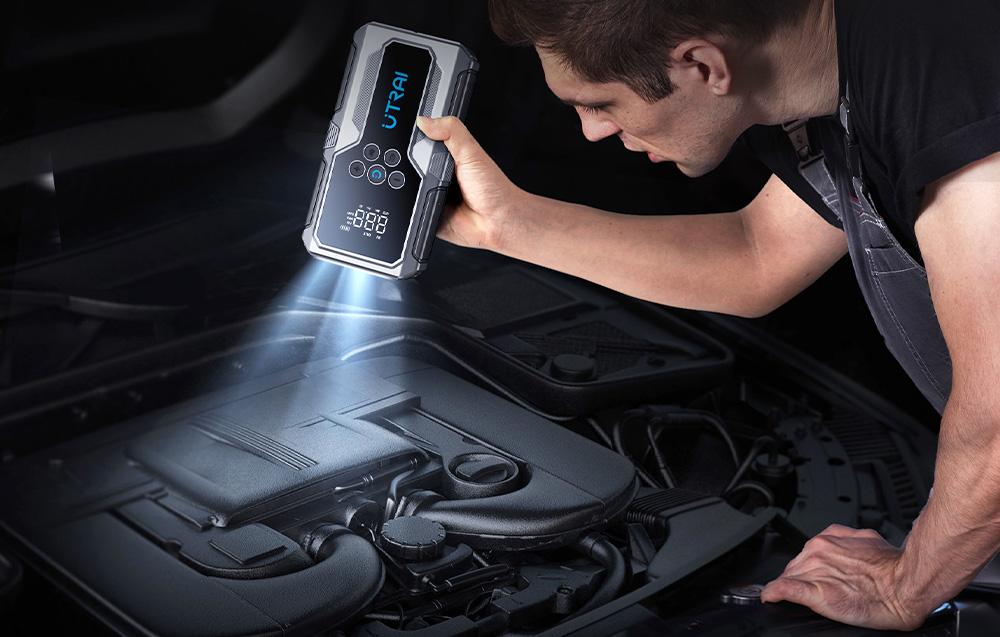 A man looks under the hood of a car and illuminates the engine with the flashlight built into the starter.