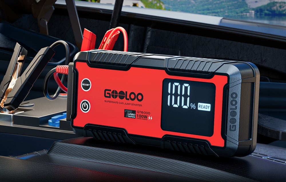 Car jump starter placed in a car with a visible display showing 100%