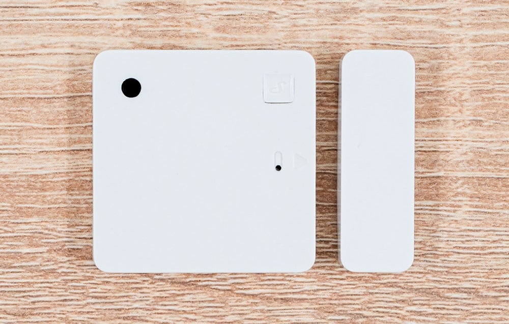White door and window sensor on a light wooden table