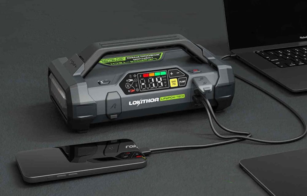 A device charging both a smartphone and a laptop simultaneously using two cables.