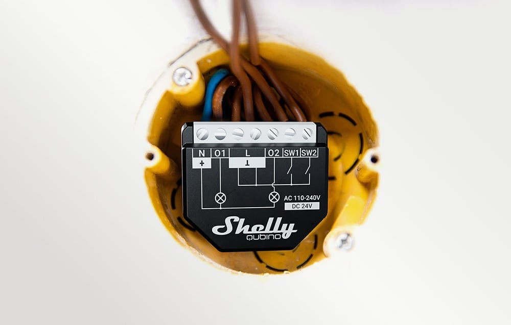 The interior of a yellow mounting box, with a black light switch and electrical wires inside.