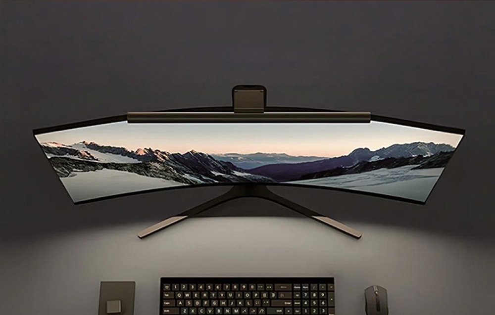 Top view of a curved monitor with a mounted Yeelight lamp; a keyboard and mouse are in front of it
