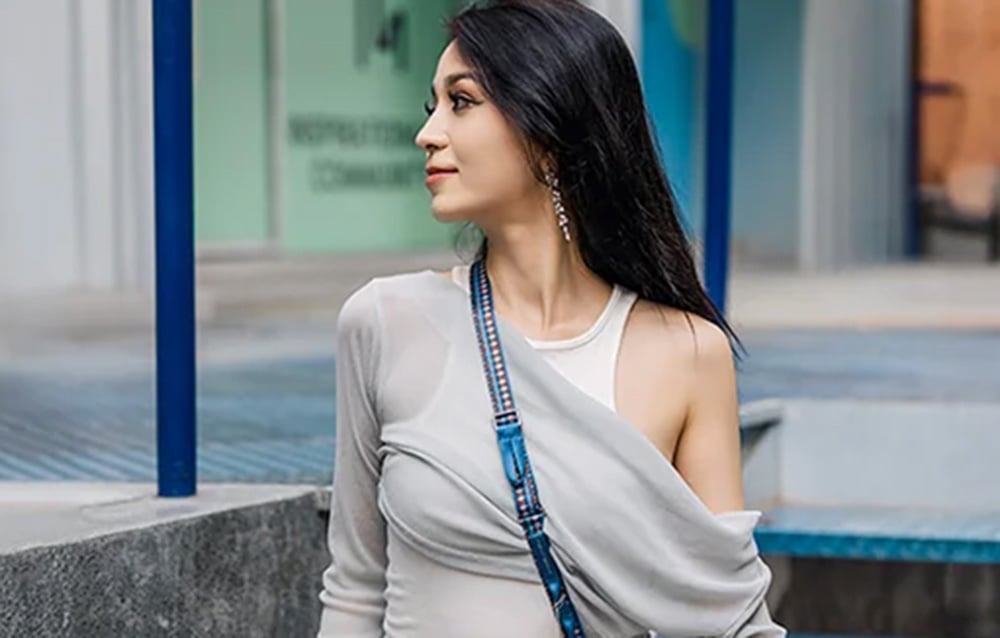 A woman with black hair wears a PGYTECH strap slung over her shoulder