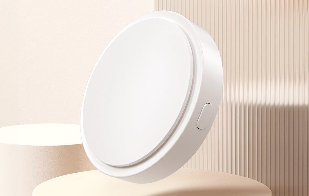 Close-up view of white sensor with side button, set against a bright background