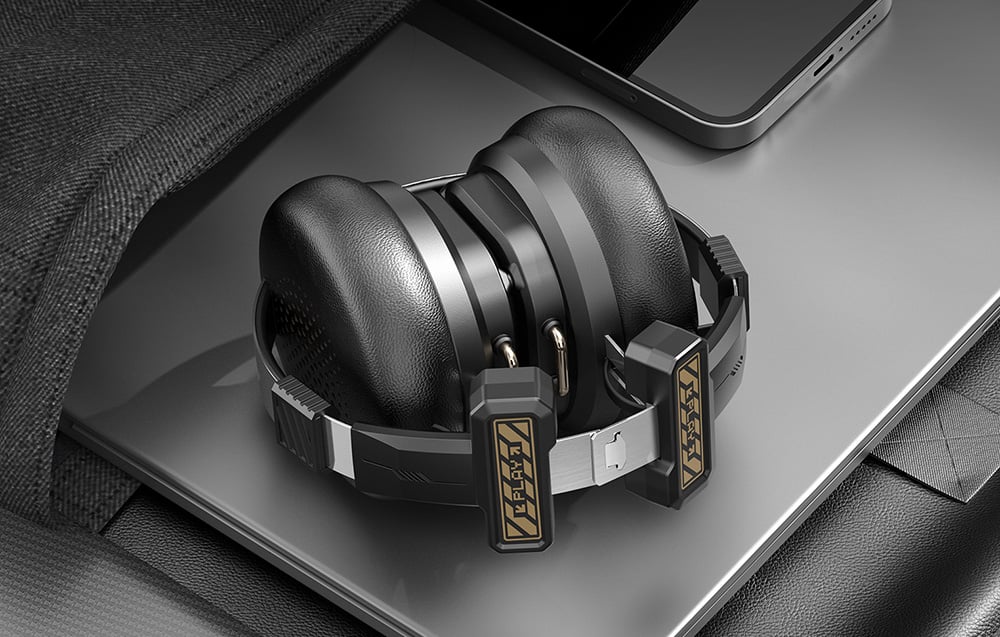 Folded Onikuma headphones being put into a bag with a laptop and smartphone