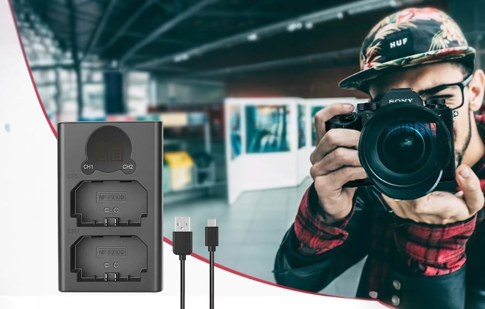 A dual battery charger with a USB cable next to a photographer taking a photo with a camera.