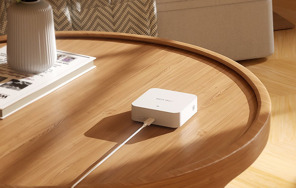 MEROSS Smart Wi-Fi Gateway connected to a cable, resting on a wooden table