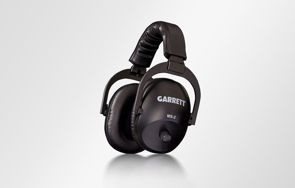 Black metal detector headphones standing on the side against a light background