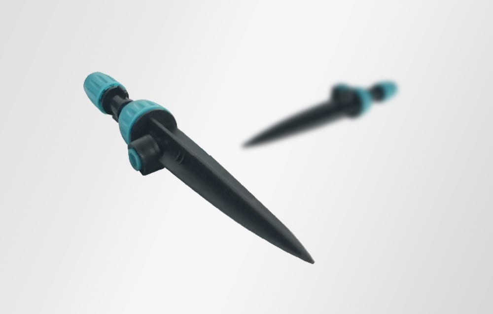 Black irrigation spike with a turquoise knob in the foreground and a second, blurred spike in the background