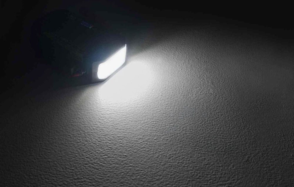 A strong white light emitted by the device’s built-in lamp, illuminating a rugged surface in the dark.