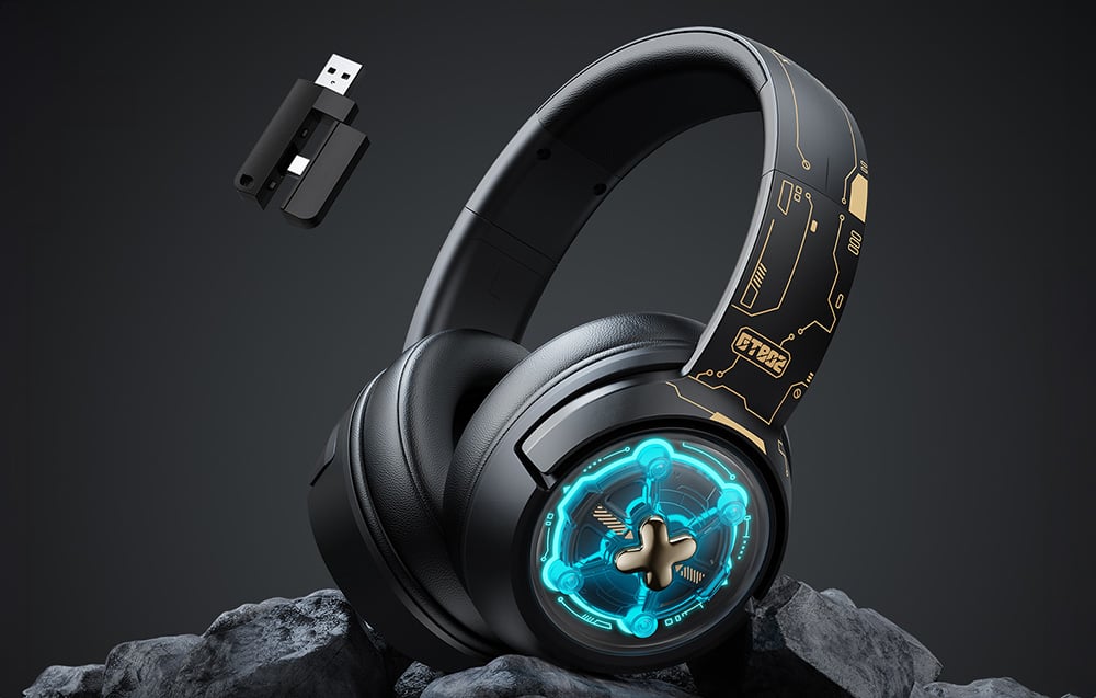 Black gaming headphones lying on rocks, with a USB adapter floating nearby