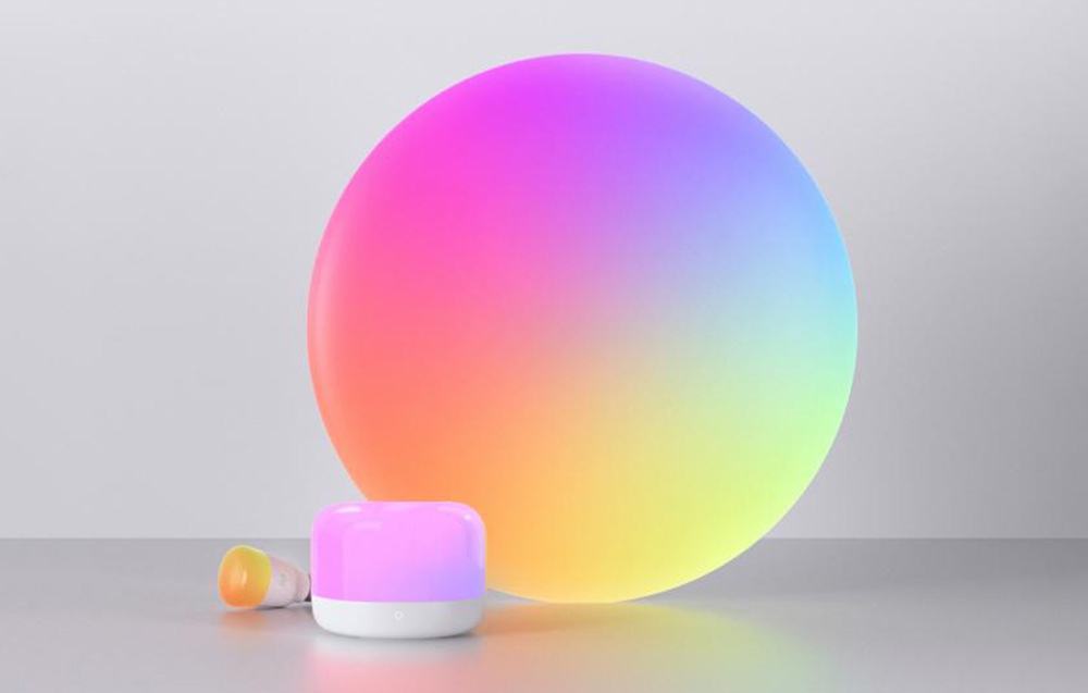 Zestaw lamp RGB z dużym okrągłym panelem i małym cylindrycznym urządzeniem, emitujących kolorowe światło.