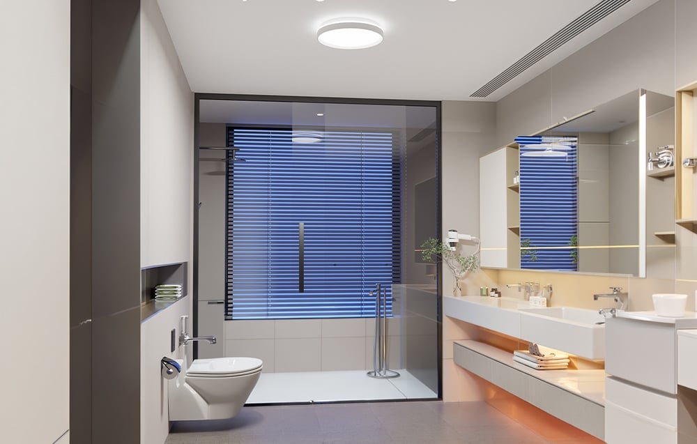 A modern bathroom with an illuminated cabinet, sink, white toilet, and a shower stall with blinds.