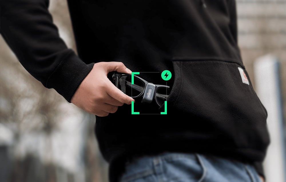 The user pulls the smart glasses, with the lightweight BOBOVR CG2 battery clip attached, out of their sweatshirt pocket.