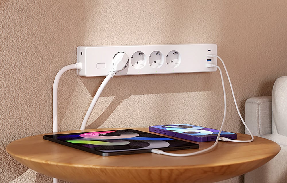 White power strip with three connected devices lying on a round table, including a phone and tablet