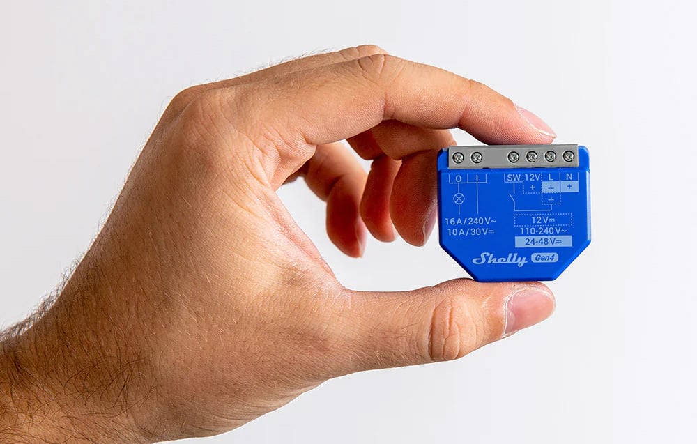 The Blue controller held in hand, showing the connection diagram and screw terminals on top of the housing.