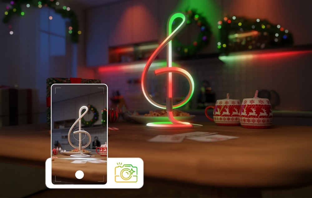 A smartphone screen facing a red-and-green desk lamp standing on a table with holiday mugs.