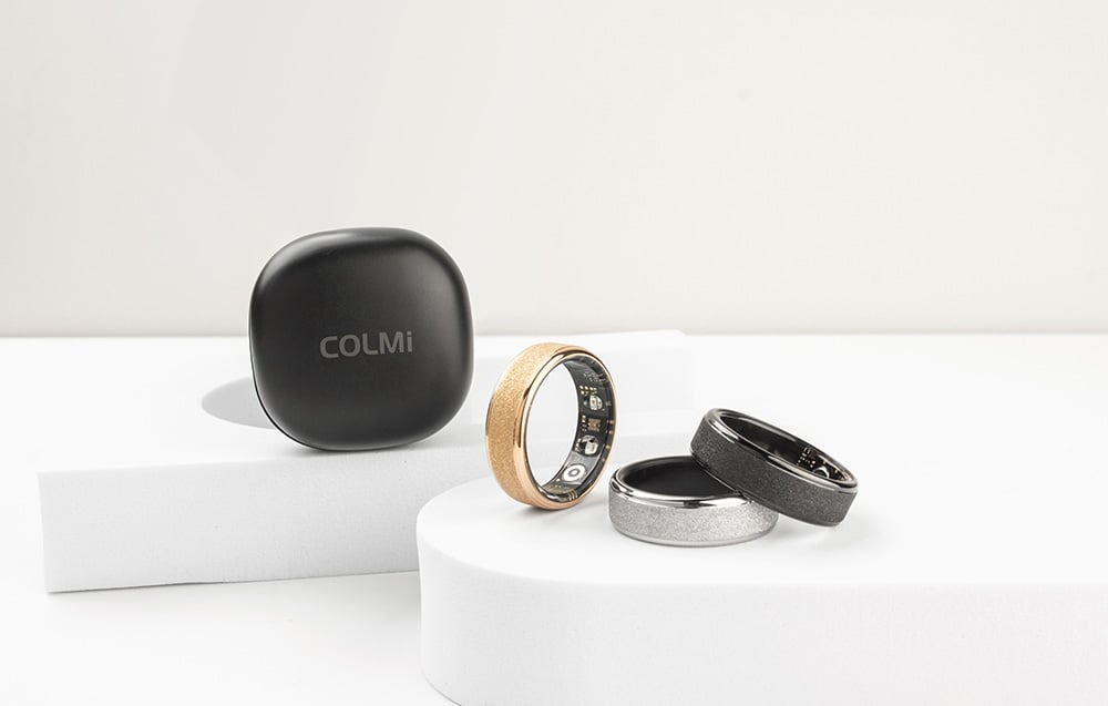 3 smartwatches and Colmi charging case on white platforms.