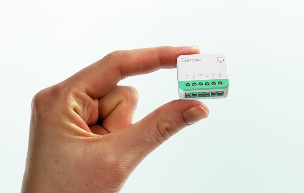 A person holding the compact Sonoff Mini Extreme module between his fingers