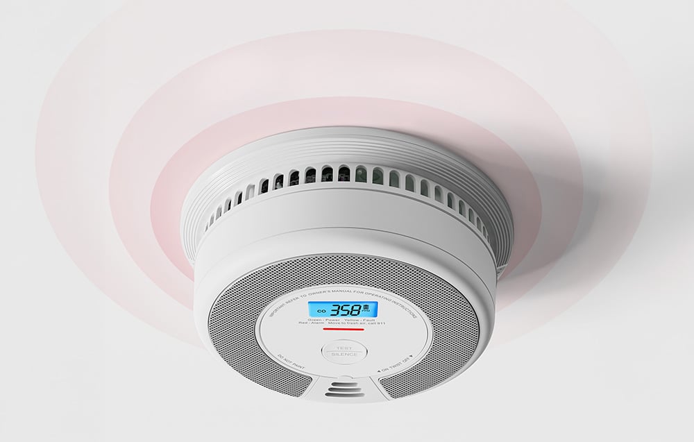 A ceiling-mounted carbon monoxide sensor with an LCD display showing 358 PPM and emitting sound waves.