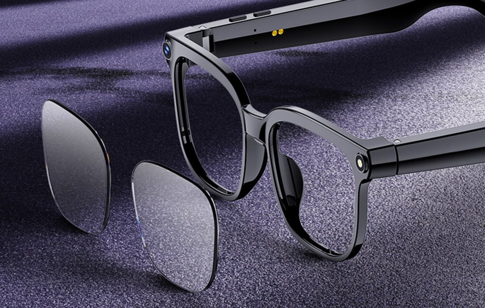Black glasses with the lenses removed, lying on a purple fabric.