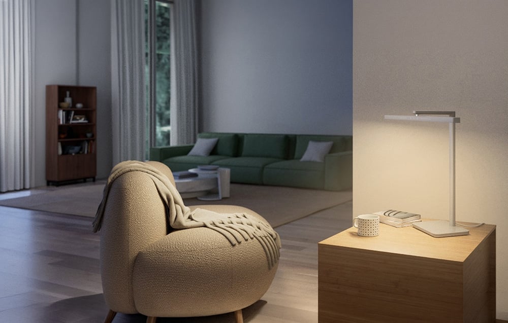 A modern, minimalist lamp standing on a wooden dresser in a living room with a Scandinavian armchair