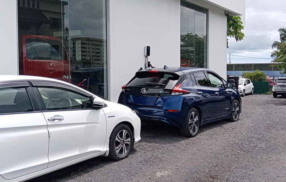 An electric vehicle connected to a charging station mounted on the wall of a building.