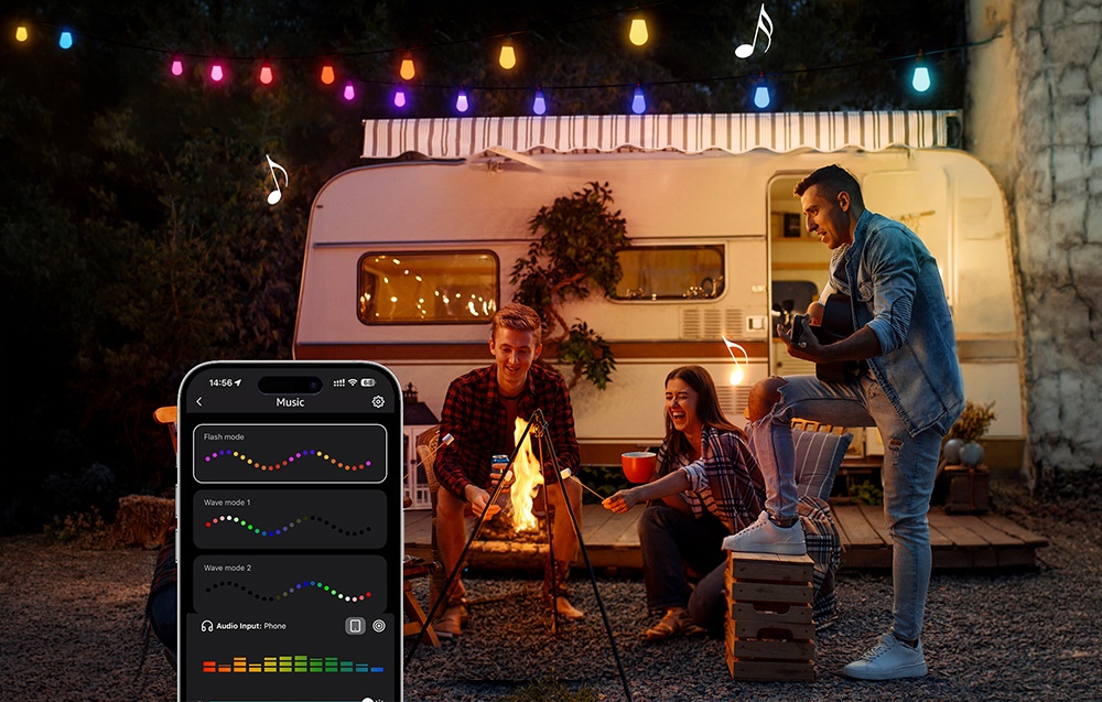 Three people by a campfire and a camper trailer under a hanging string light; a phone with a music app is visible to the side.