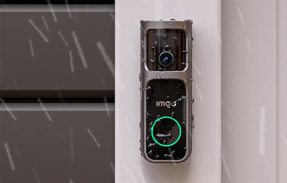 An Imou video intercom covered in raindrops during a rainstorm, mounted on a white post