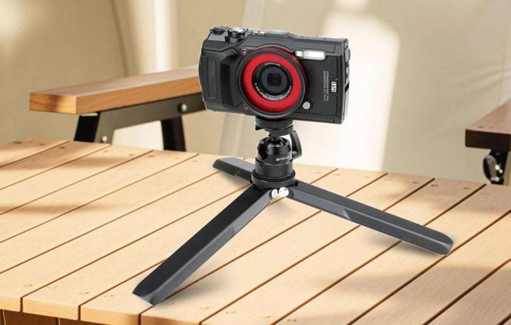 Camera with red ring on table tripod on wooden table