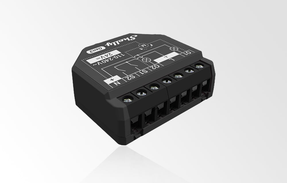 Angled view of a black Shelly 2PM Gen3 module against a light gray background, with six connectors and a printed wiring diagram