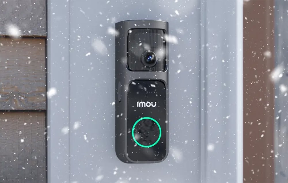 An Imou video intercom mounted on a wall during heavy snowfall