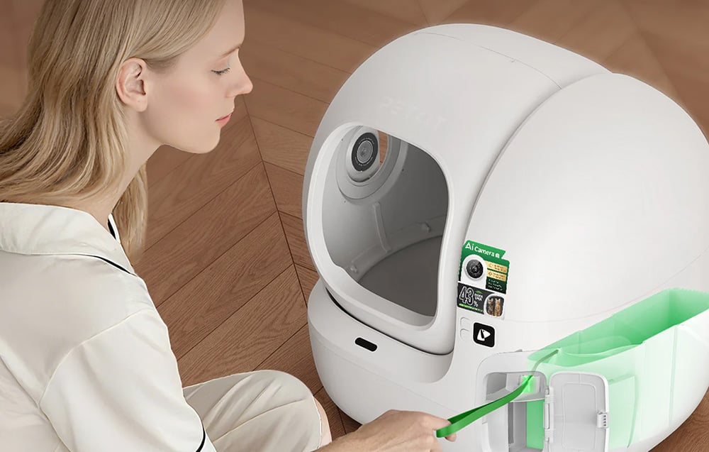 Woman pulling out a green waste bag from the side compartment of the automatic cat litter box