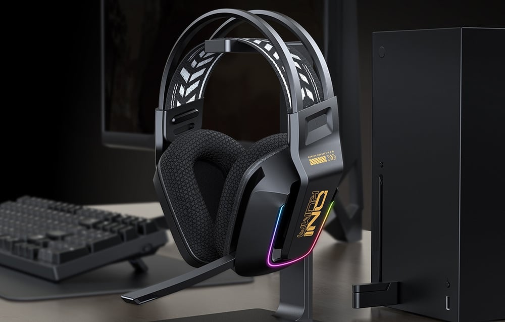Gaming headphones on stand next to keyboard and black PC on desk