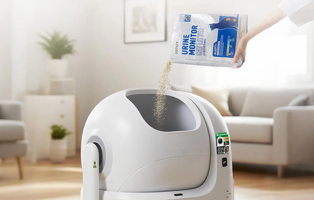 A person pouring PETKIT litter into the open drum of an automatic litter box
