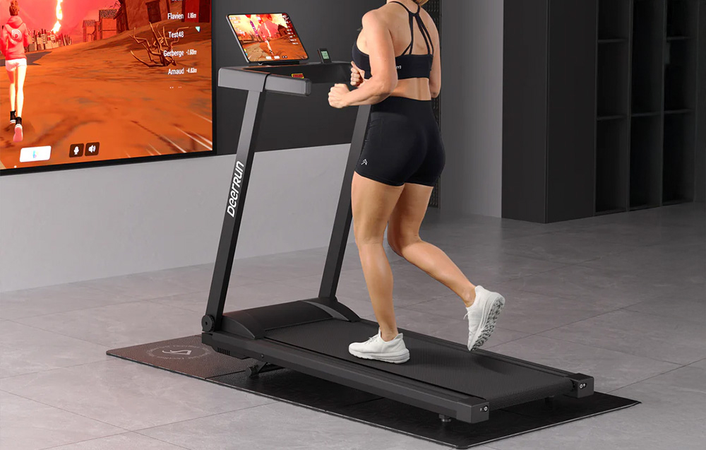 A woman runs on a treadmill in front of a screen with a game in a modern room
