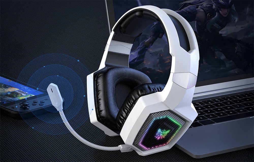 Onikuma headphones with extended microphone lying next to a portable console and laptop computer
