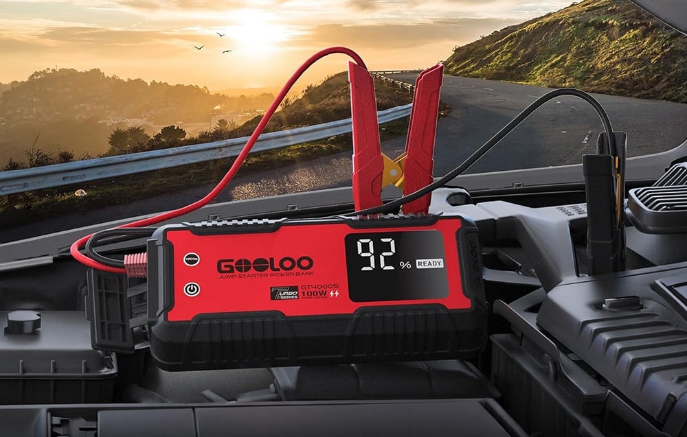 Car starter connected to a battery in the engine compartment with a visible 92% charge level