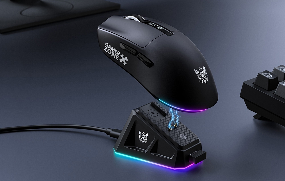 Black Onikuma gaming mouse with backlighting above the charging base on a black desk next to a keyboard