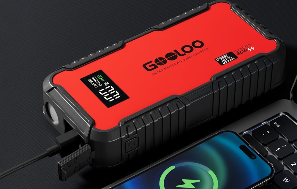 Car starter charging a smartphone lying next to it on a surface