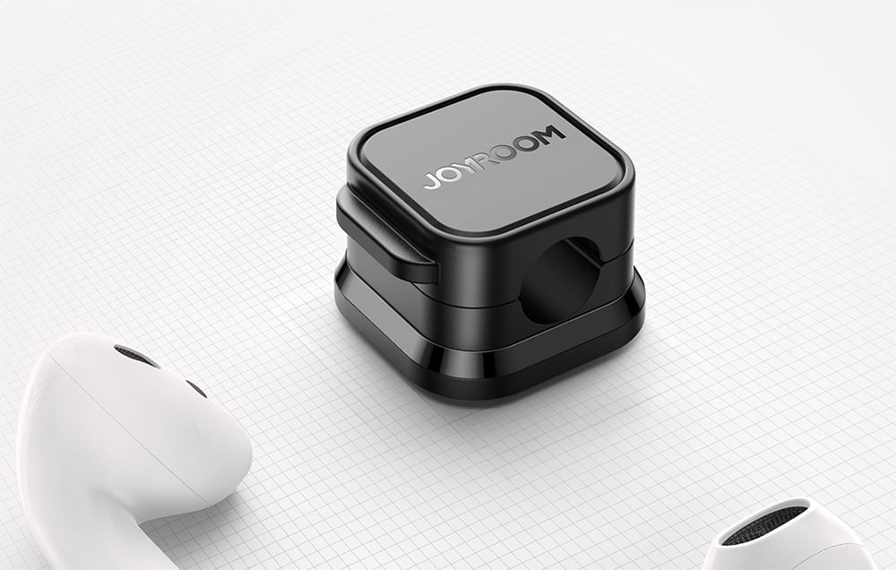 Black cable organizer lies on a piece of paper next to the white TWS handset
