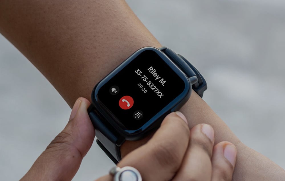 Close-up of a black smartwatch on a wrist, displaying an incoming call from Riley M