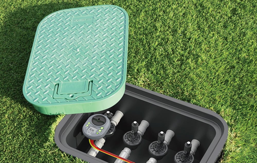 Irrigation controller mounted inside an underground valve box located in a green lawn