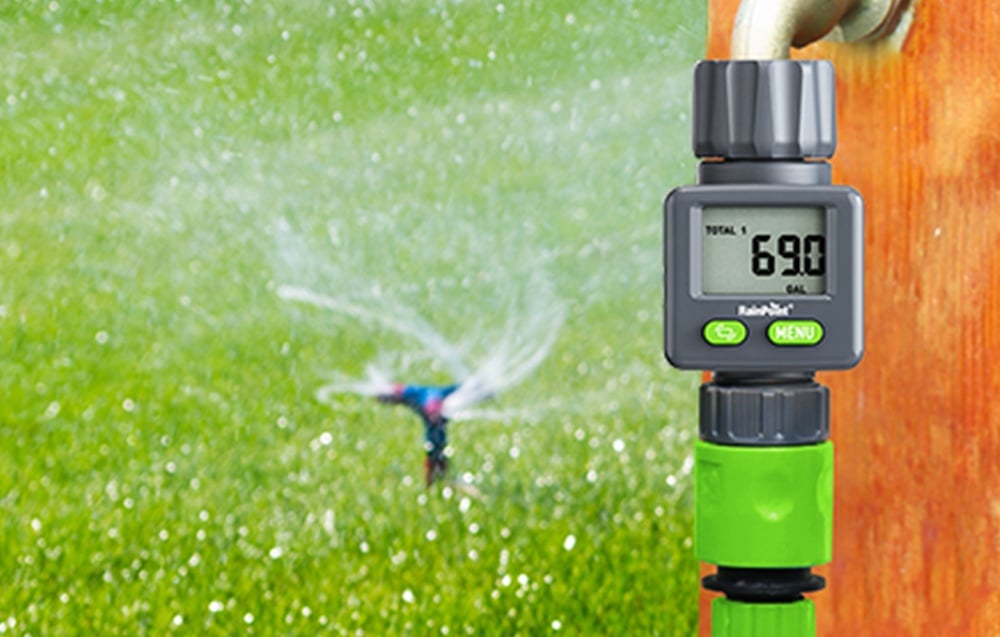 RainPoint digital water flow meter mounted on a garden tap with a sprinkler gun running in the background.