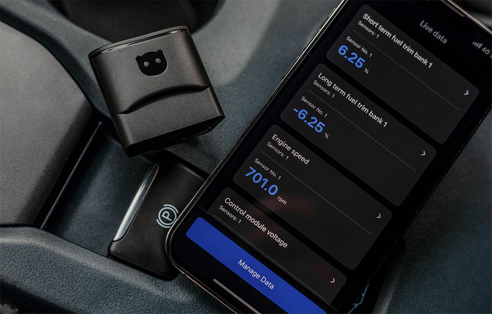 Carly adapter and smartphone displaying vehicle diagnostic data: fuel level and module voltage