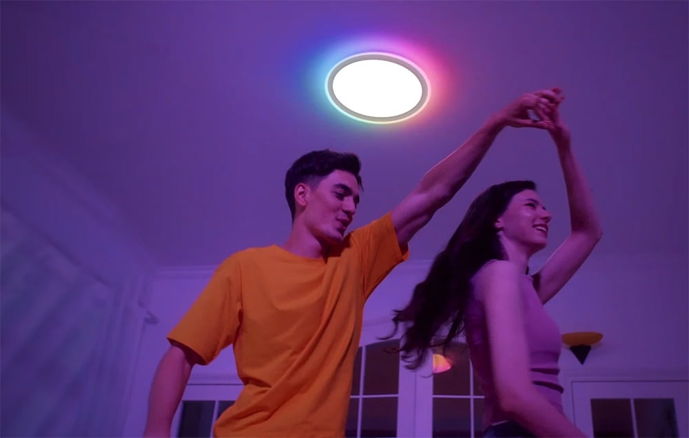 Couple dancing in a room illuminated by Yeelight Mars C400 lamp emitting multicolored light.