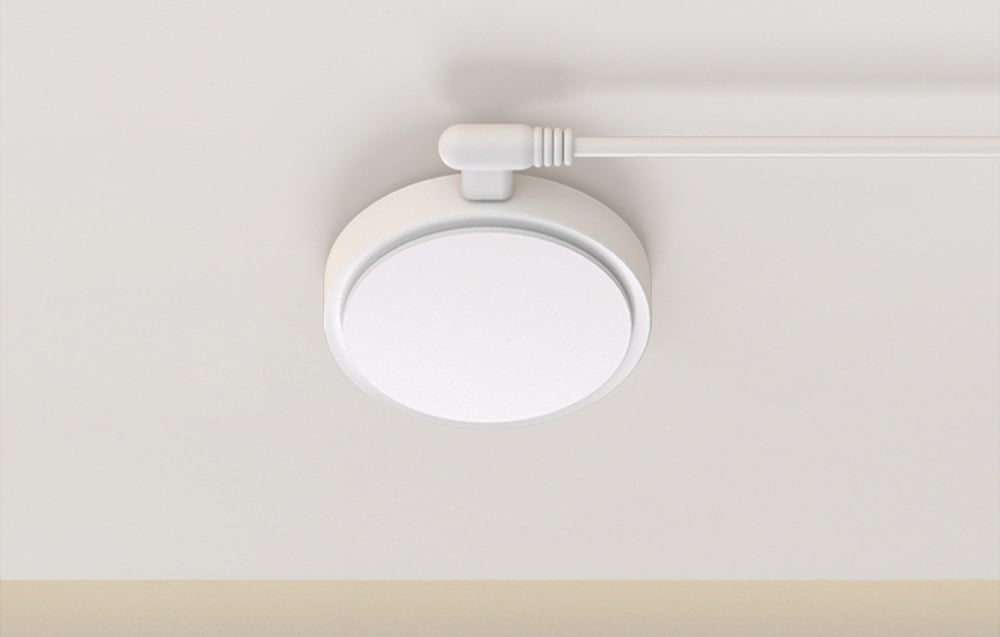 Top view of ceiling-mounted white sensor with wire