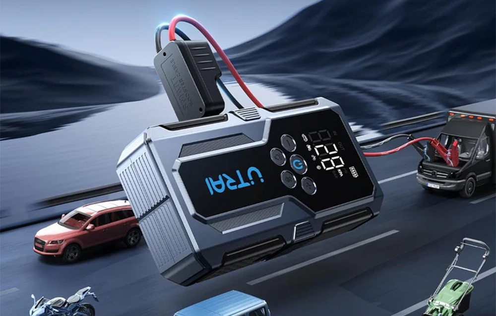 Car jump starter with jump cables connected, set against a backdrop of a road, a motorcycle, and cars.
